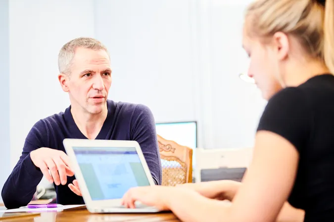 Two people talking, while using laptop