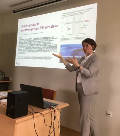 A lady in grey suit teaching in front of a slide show