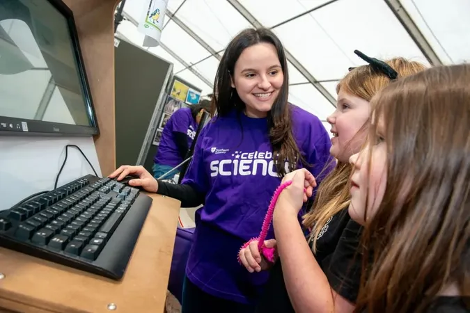 Person wearing a Celebrate Science top helping children on a computer