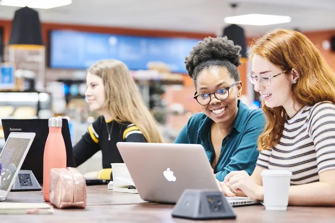 Three students talking and studying at their laptops