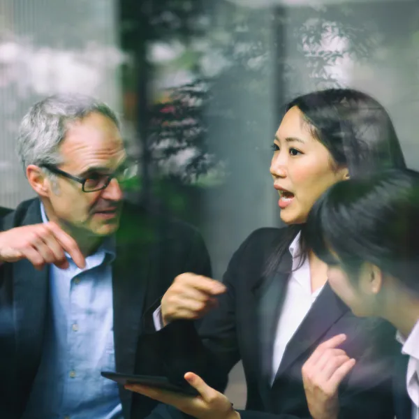 Three business people actively discussing near a window