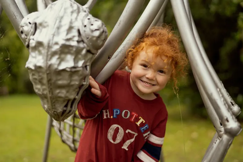 A child smiling under a sculpture at the botanic Gardens