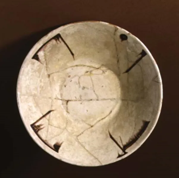 View from above of the inside of a white ceramic bowl, decorated with a style of angular writing known as Kufic.