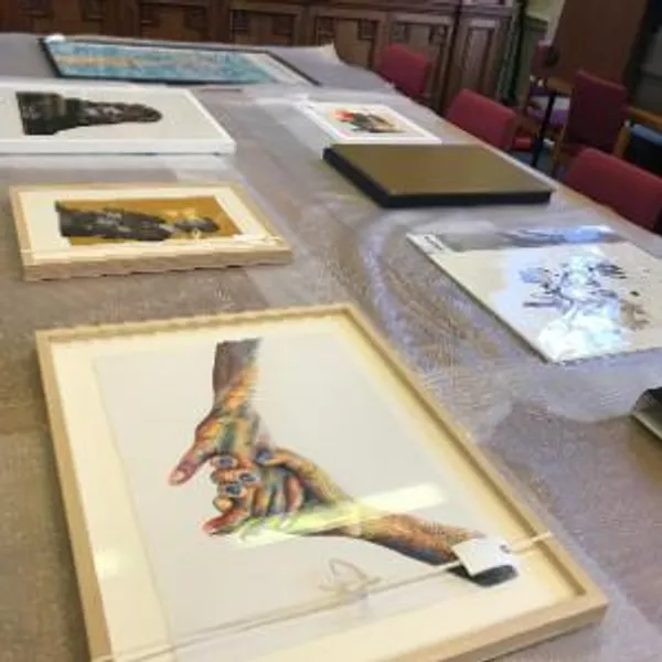 A selection of framed artworks sit on a table covered in bubble wrap.