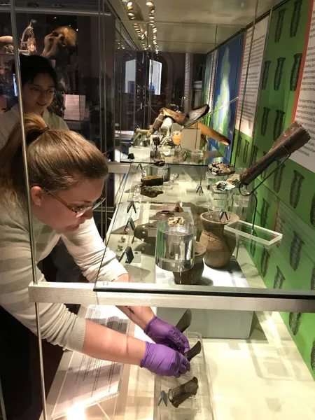 Two students are installing Bronze Age axe head in the Museum of Archaeology