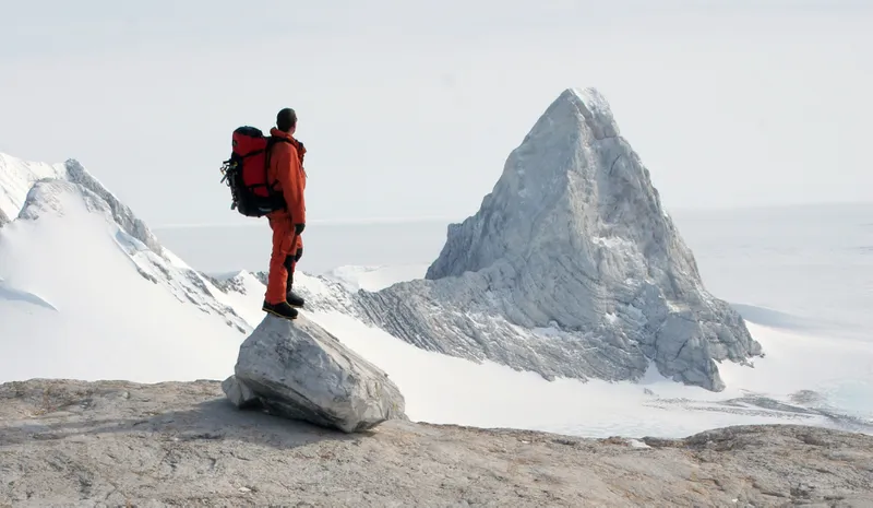 Person stood on a large rock with snow and ice surrounding them