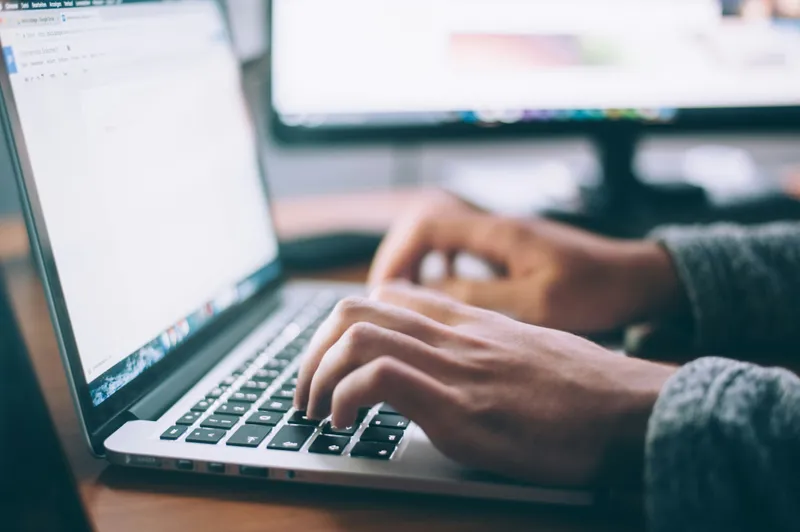 Person writing on a laptop with icons overlaid