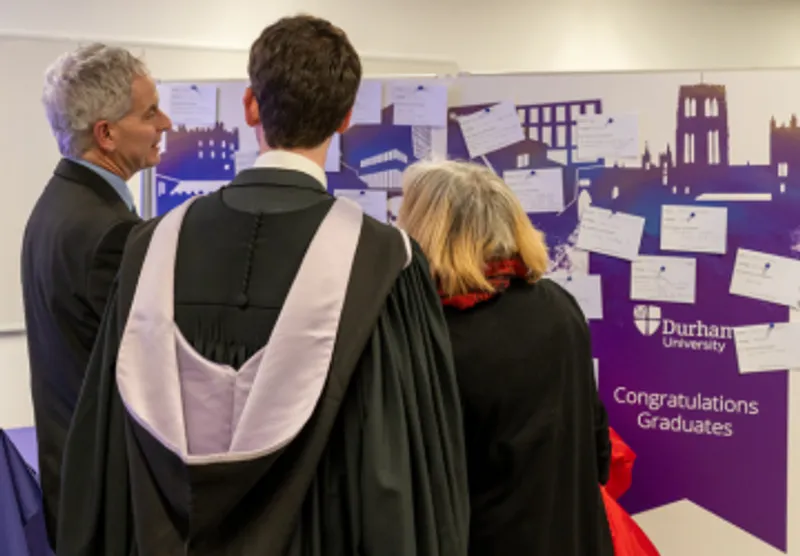 Graduate and parent reading congregation memory wall
