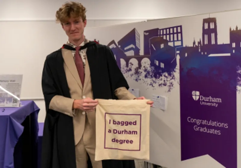 graduate holding tote bag by memory board at winter congregation