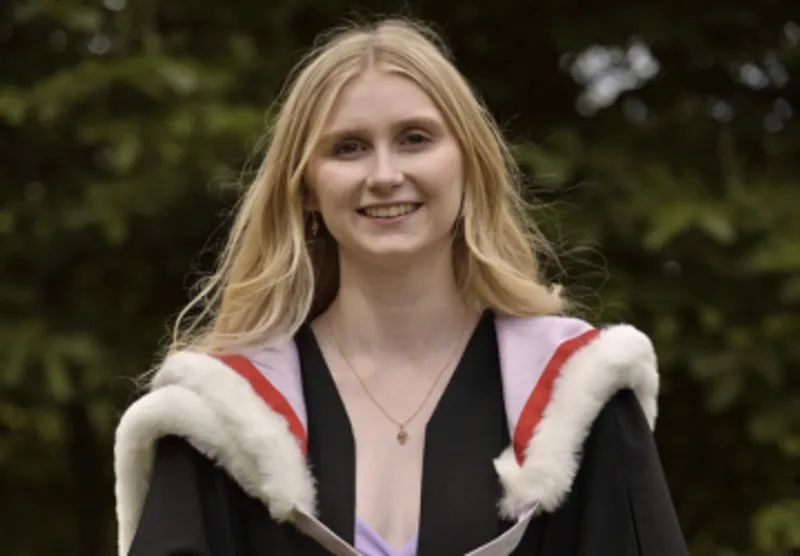 Alex smiling at camera with her graduation robes on
