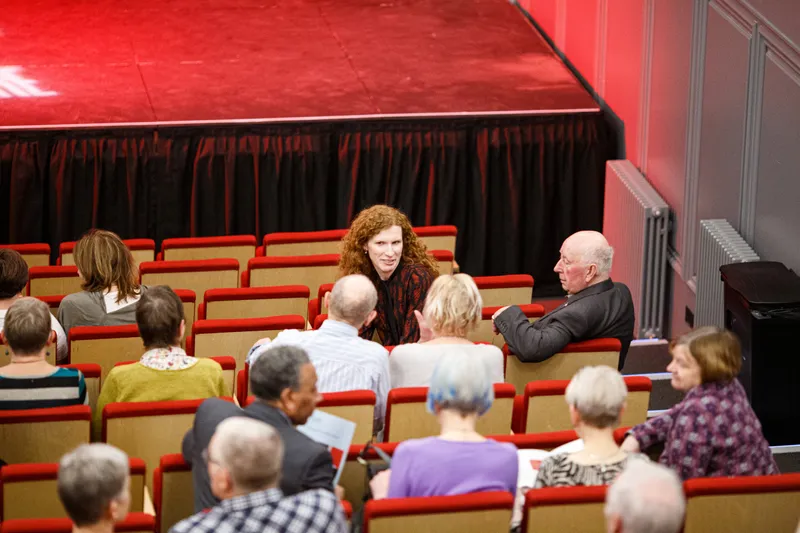 Audience members chatting in their seats at the theatre