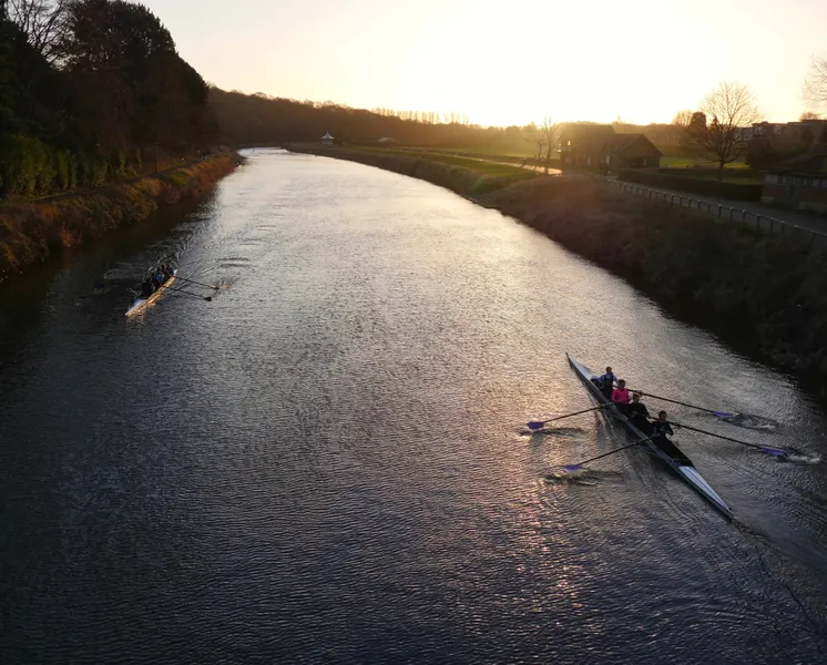 Silhouettes of two boats of rowers on the River Wear