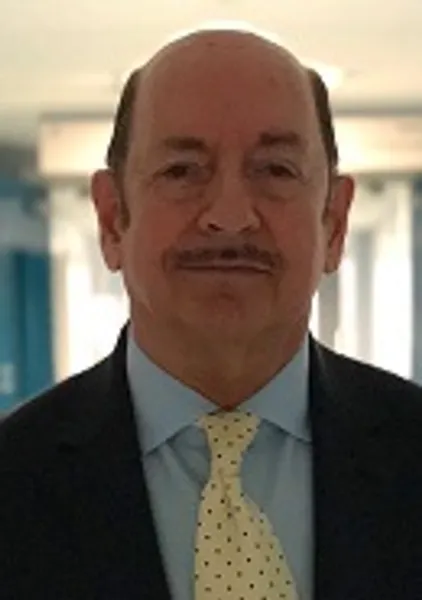 A man with a moustache, blue shirt and yellow tie