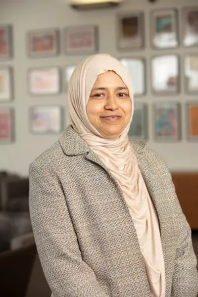 A women wearing a jacket and a headscarf smiling at the camera