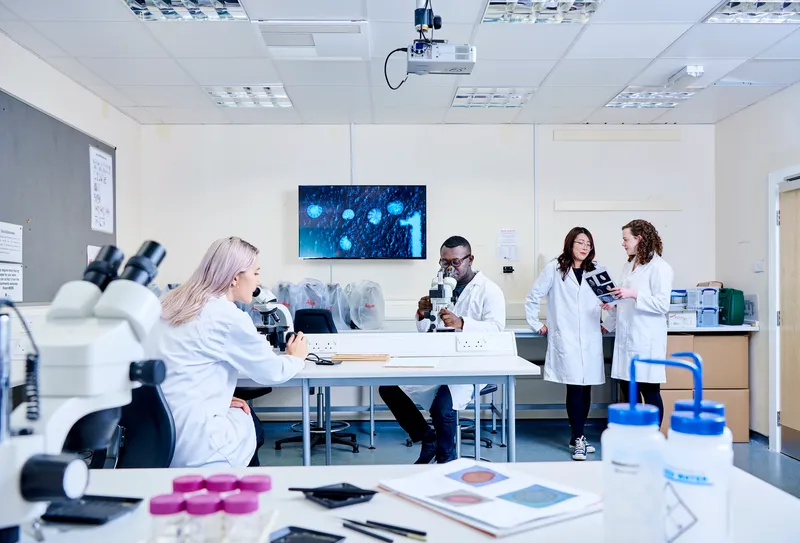 A group of students in white labcoats conducting research in a geography laboratory