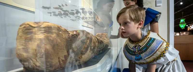 A child wearing Egyptian fancy dress looks at an Oriental Museum exhibit