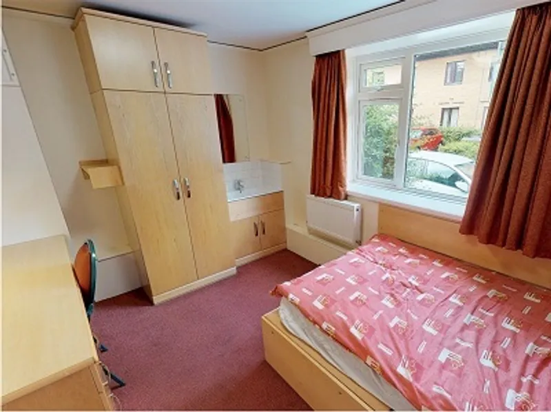 Student bedroom with a single bed, wardrobe, cupboards and desk