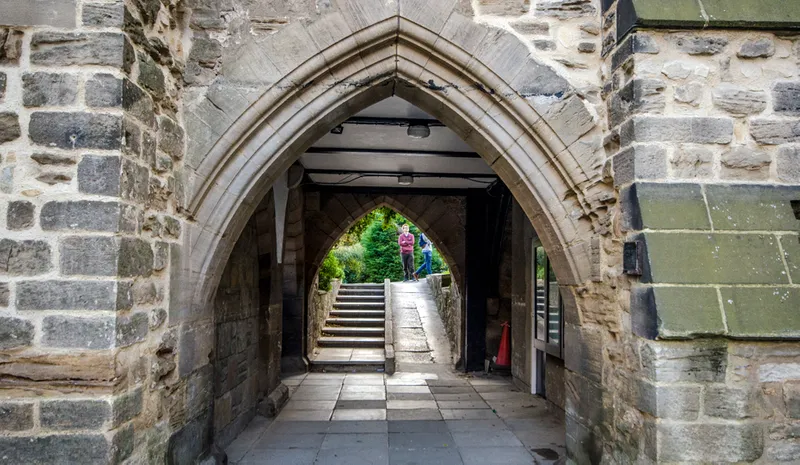 The college grounds chapel archway, people stand talking on the other side