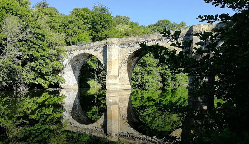 View of the River Wear to historical Prebend’s Bridge arches in the summer sunshine.