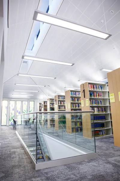 Staircase leading up to the library floor with rows of book shelves