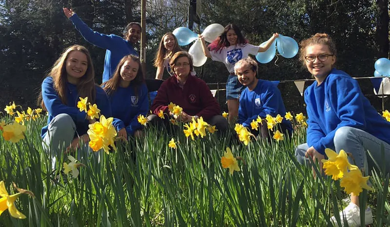 Students waving and smiling in the grounds of Trevelyan College