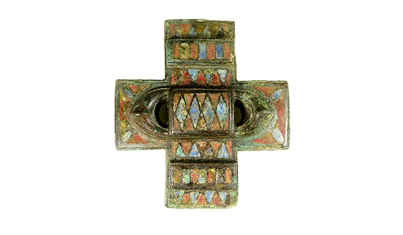 A gold brooch with red and blue enamel inset in the shape of a cross