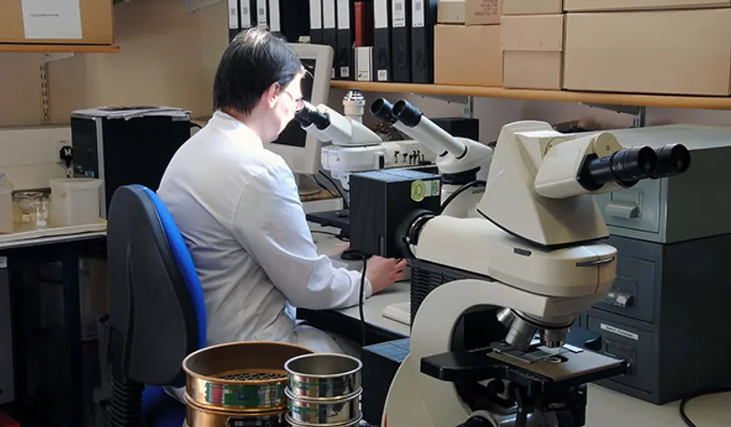 A person sitting at a microscope in a lab