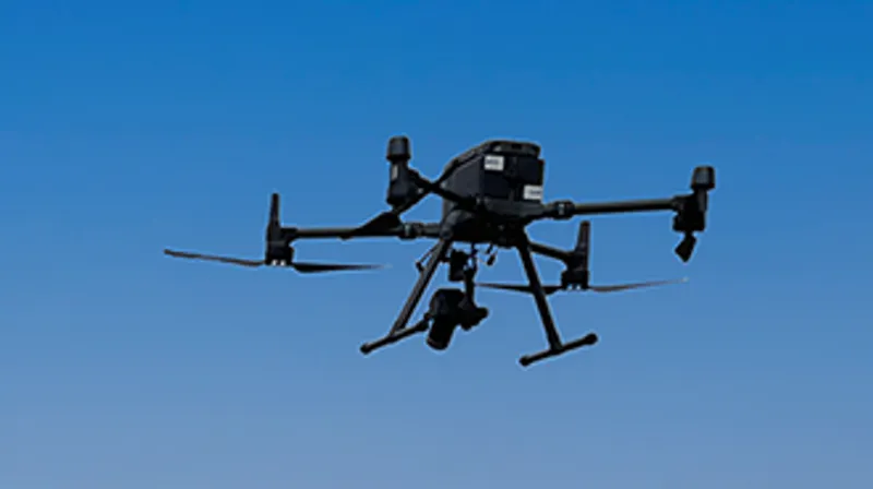 A UAV or drone with a camera attached flying in clear blue skies