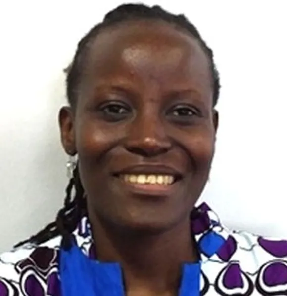Front facing photo of a smiling Dr Nancy Rushohora in front of a white wall.