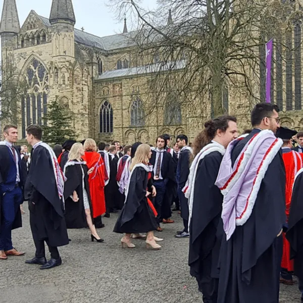 A group of students in gowns outside Durham Cathedral