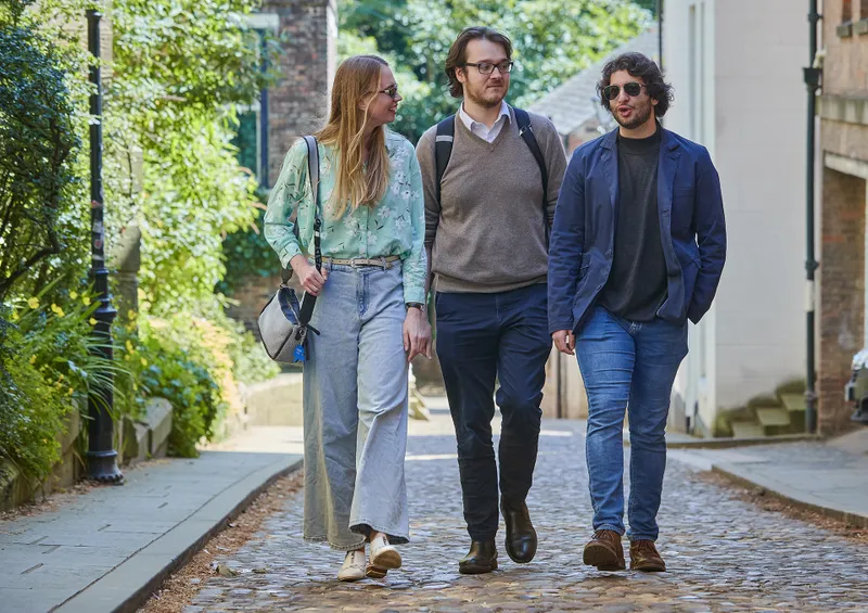 Three Classics postgraduate students walk next to each other talking