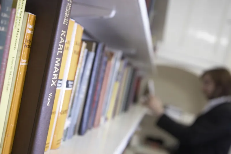 A shelf of books in a library with a student browsing
