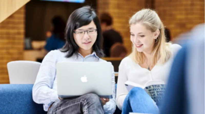 Two female students are looking at a laptop.