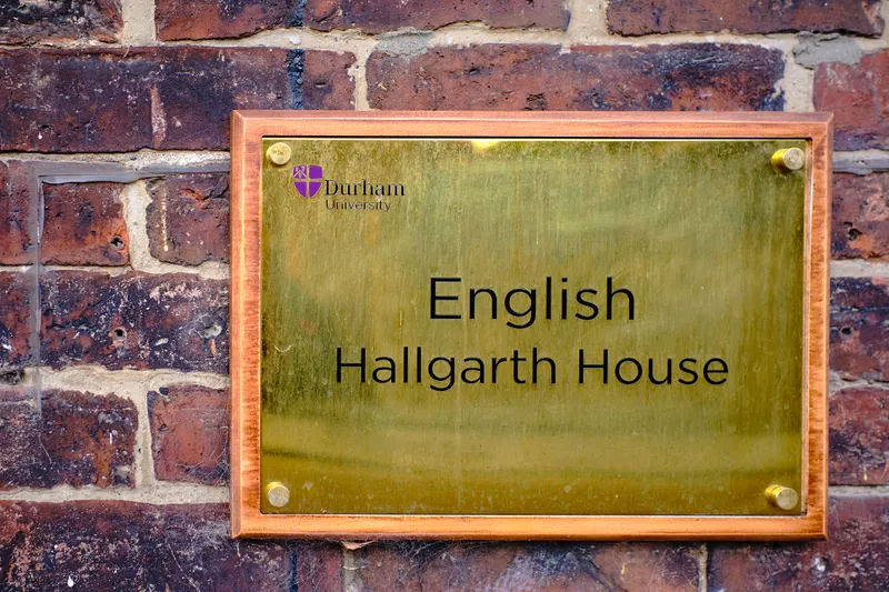 A brass wall plaque displaying the text 'English Hallgarth House'