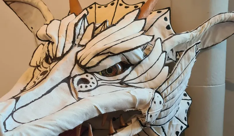 Close up of a white dragon puppet with fierce yellow eyes