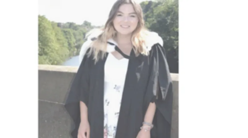 A picture of a student wearing a black and white graduation gown.