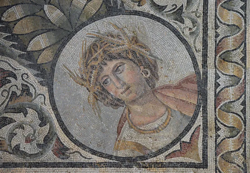 Mosaic depicting an image of a human's face with a crown of leaves