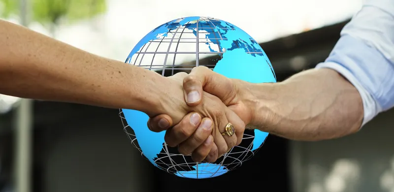 Shaking hands in front of a globe