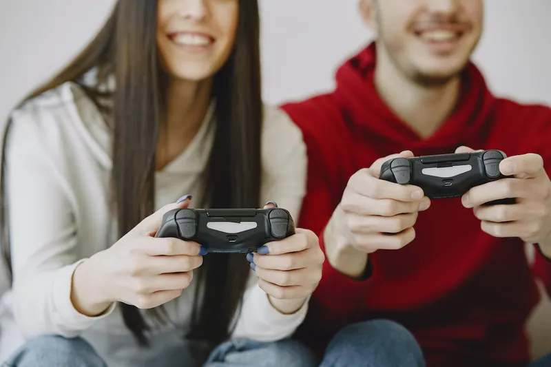 Two people sitting down, smiling and holding gaming controls
