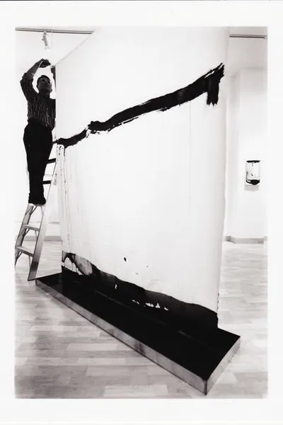 Man on ladder, hanging a painting