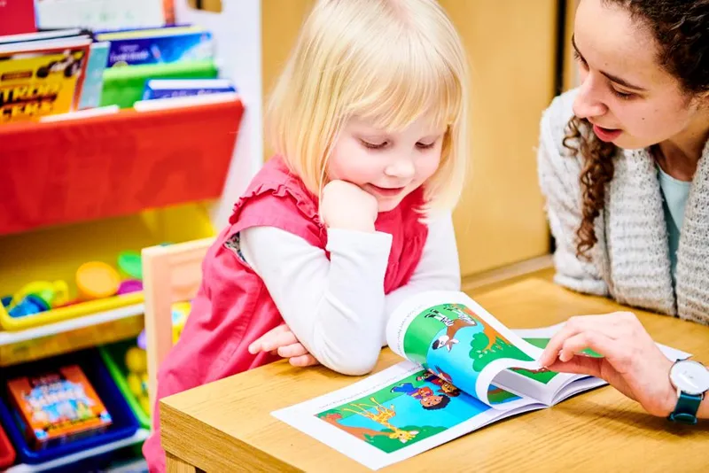 A child with researcher examining a picture, taking part in development research practical