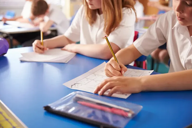 Children writing on paper in a classroom