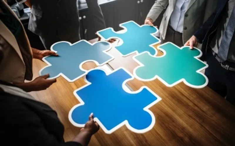 Team of four connecting giant jigsaw pieces together on a table