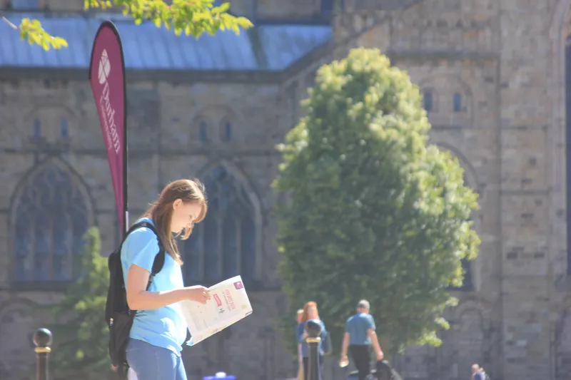 Potential student reading a brochure outside Durham Cathedral