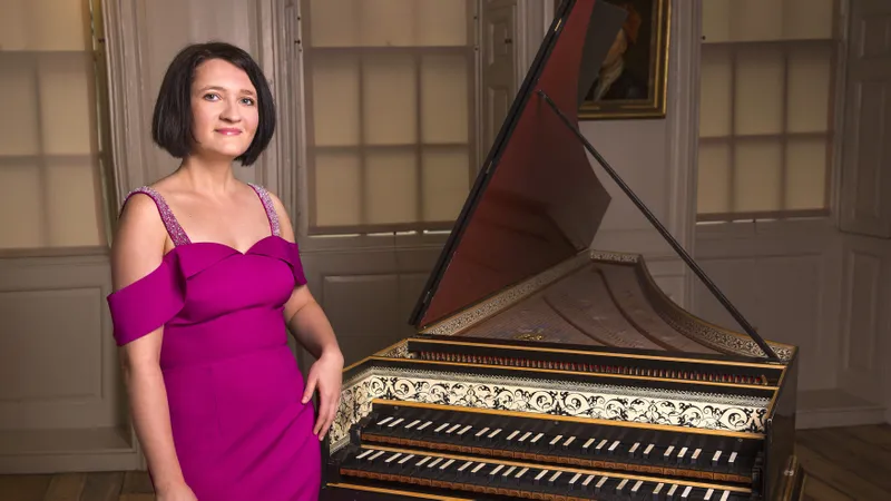 Katarzyna Kowalik standing in front of a harpsicord in an evening dress