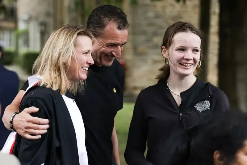 A student in a gown with two guests outside Durham Cathedral