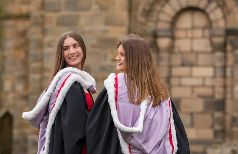 Two graduands in robes outside Durham Cathedral