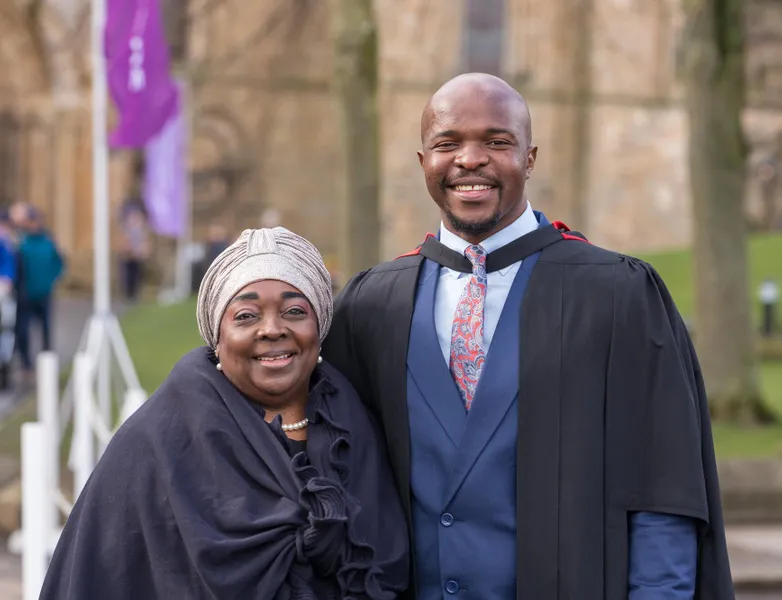 Graduate in robes smiling with guest