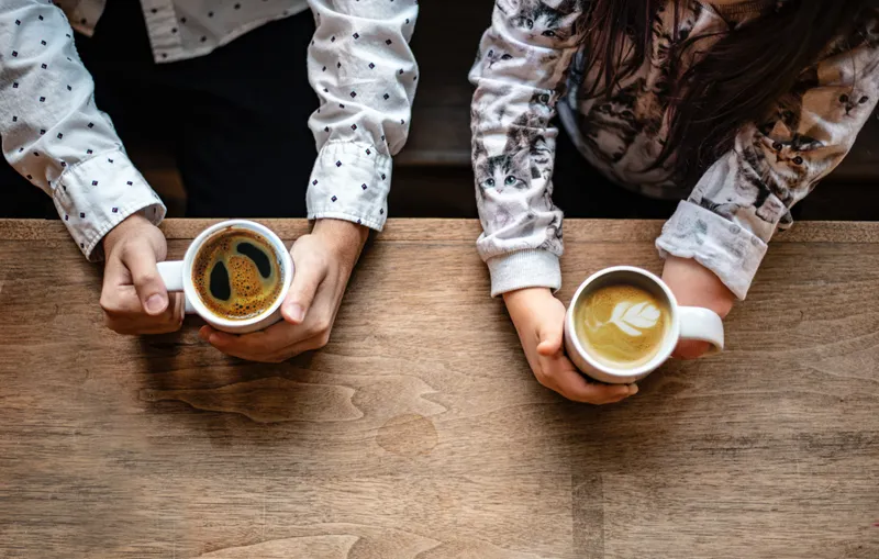 Image of two people holding coffee one with a disability