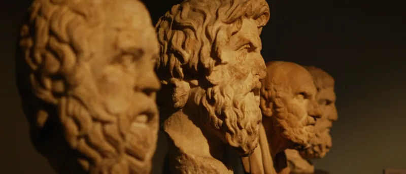 Stone busts of ancient philosophers against a dark background